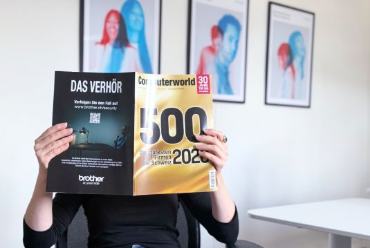Computerworld-Magazin mit dem Cover ‚500 – Die stärksten ICT-Firmen der Schweiz 2026' wird aufgeschlagen vor dem Gesicht gehalten.