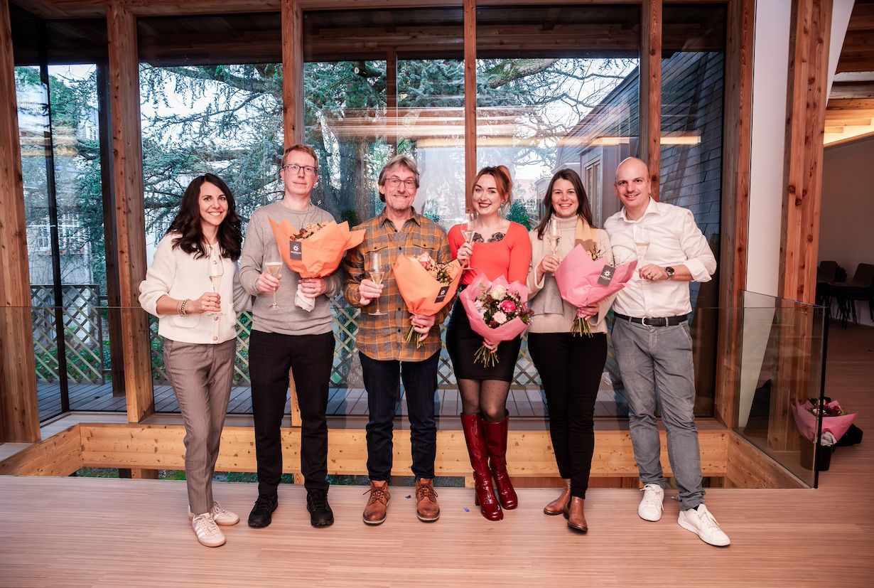 Group photo with Denise, Pete, Dominik, Katharina, Chris; they hold flowers and champagne glasses and smile at the camera