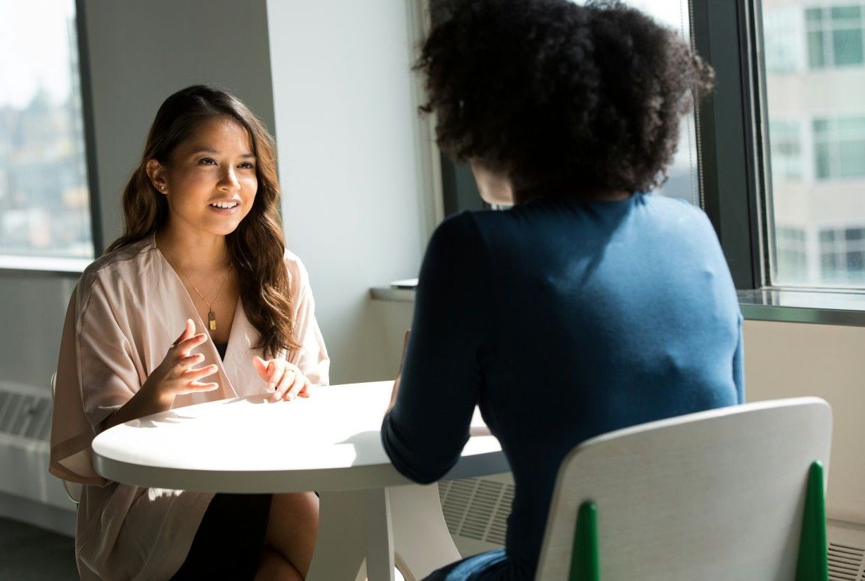 Two women chatting at a round table.
