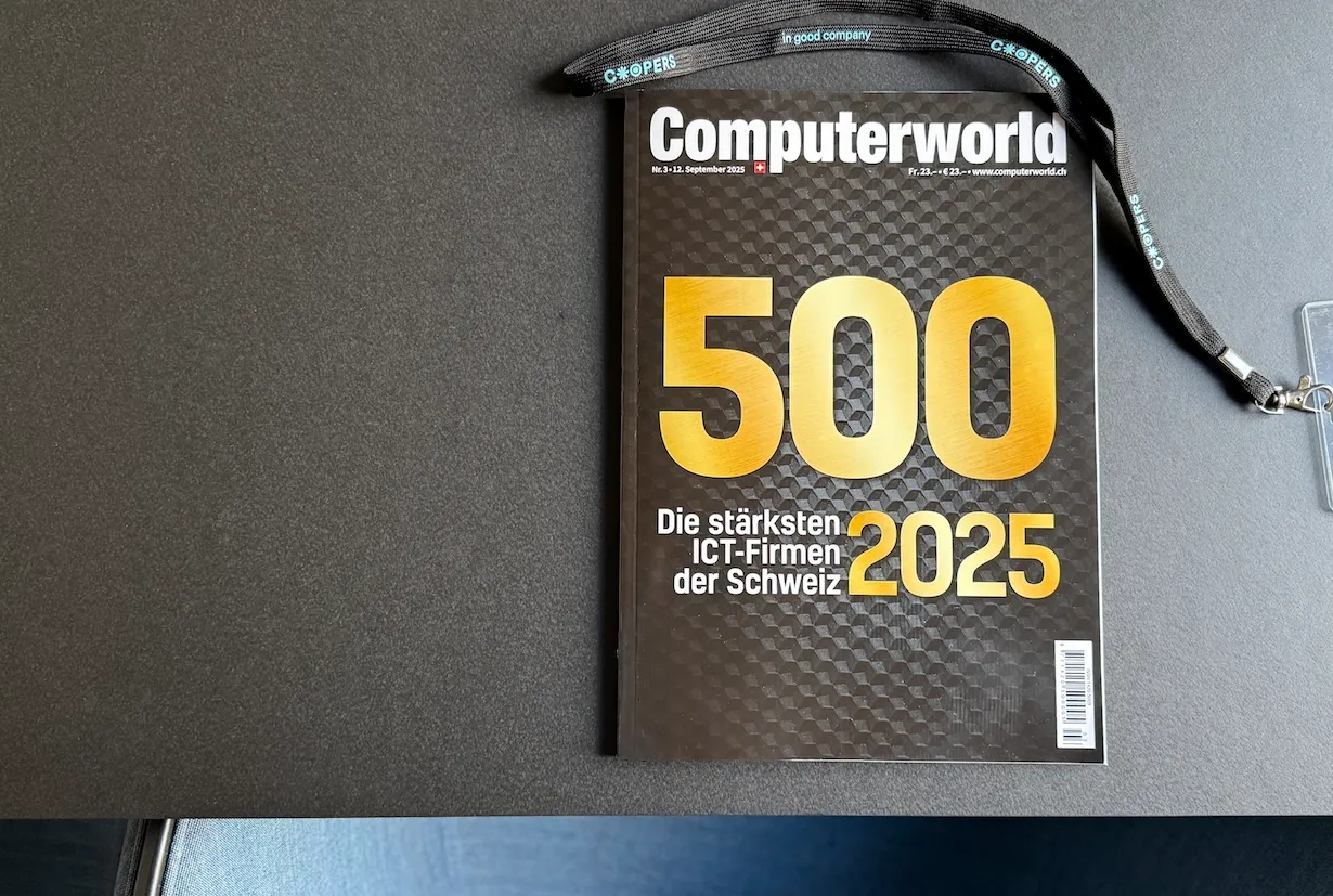Titelbild des Magazins Computerworld 500 – Die stärksten ICT-Firmen der Schweiz 2025 auf einem dunklen Tisch, daneben ein Coopers-Lanyard.