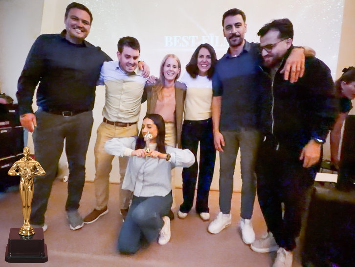 Das Team des Western ‹Die Karte der Freiheit›, Gewinner für den besten Film, posiert Arm in Arm vor der Leinwand in der Orangerie Basel, eine Kollegin kniet vorne, daneben steht eine goldene Statue.